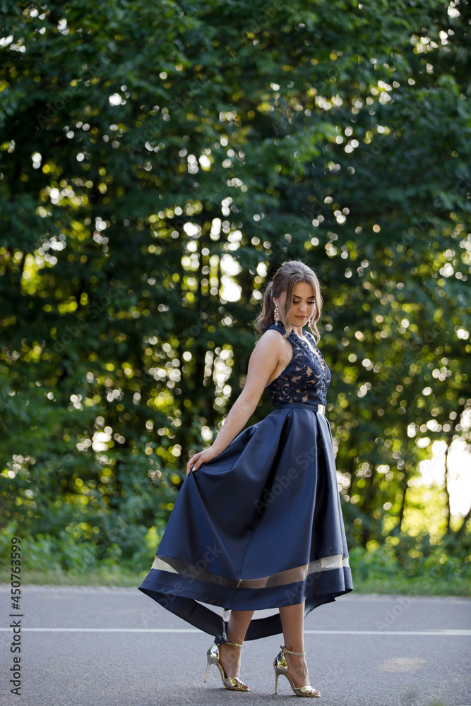 Poster caucasian female from bosnia and herzegovina in an elegant blue dress with trees in the background