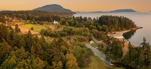 Aerial View of a Summer Sunset On an Island in the Salish Sea. Drone shot of Lummi island's Legoe Bay during an amazing sunset with an historic white church and "Lover's Bluff" in the background.