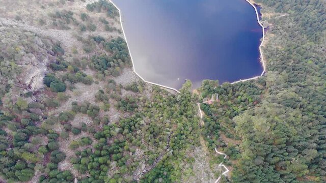 Drone shot over mountain lake above clouds. High altitude lake adove low altitude cumulus clouds at scenic mountain range and forest state park. 24 increased to 59fps, reversed video