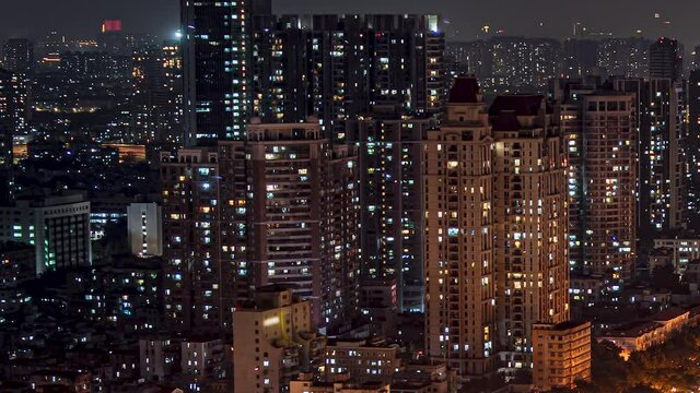 Night city high rise apartments time lapse loop. Chinese crowded city with lights turning on and off at midnight. Fast paced modern Asian night-scape time lapse in urban metropolis.