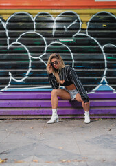 portrait of a woman wearing sunglasses on a graffiti wall