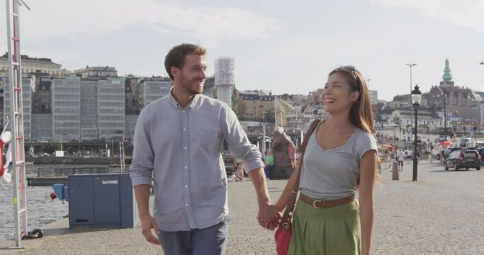Couple walking holding hands in city of Stockholm, Sweden, Europe. Happy multiracial young couple walking outside. Scandinavian man, Asian woman