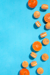 Homemade orange macarons with a mint sugar topping isolated on a bright blue background