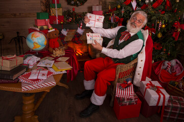 Santa Claus rejoicing with letters and mail in his post office indoors Log Cabin at the North Pole