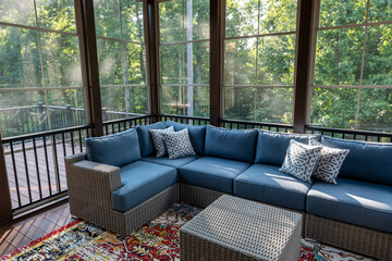 New modern screened porch with patio furniture, summertime woods in the background.