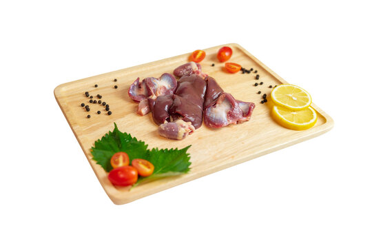 Raw uncooked chicken gizzards, stomach on wooden cutting board.