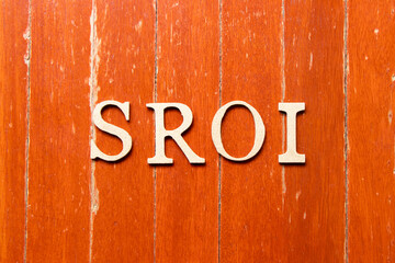 Alphabet letter in word SROI (Abbreviation of Social Return on Investment) on old red color wood plate background