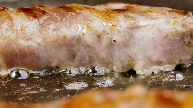 Preparation of meat dish from minced meat wrapped in bacon with white veins. The chevapchichi are fried in a hot pan in oil. Beautiful wallpaper of cooking for restaurant. Slow motion. Close up.