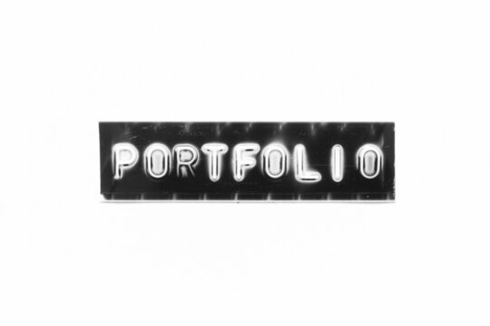 Embossed letter with word portfolio in black banner on white paper background