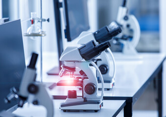 Close up shot of two eyes viewfinder scientific microscope instrument with red light flare at lens and glass plate sample in row on laboratory working desk using for monitoring coronavirus covid 19