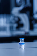 Close up shot of variety brands of coronavirus covid 19 vaccine in small glass vials and bottles on scientific laboratory table in hospital in front of blurred microscope and test tubes background