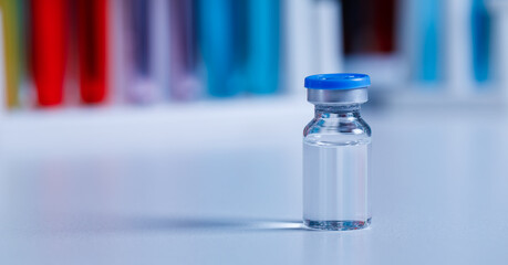 Close up shot of vaccine in small glass vial bottle with red label for protection prevention epidemic pandemic virus outbreak around world in laboratory blurred background