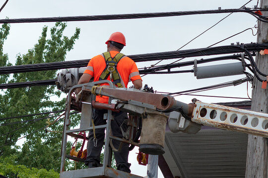 electric cable repairman lineman working climbing in articulated boom lift