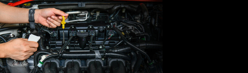 A professional mechanic is holding the oil dipstick check the oil level in car engine, copy space