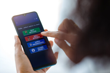 Woman holding smartphones and use finger touch on screen and selecting on buttons of buy and sell application for bitcoin or cryptocurrency digital money trading