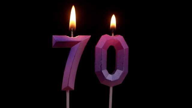 Burning birthday candles isolated on black background, number 70
