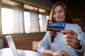 Blurred image of a business woman holding and showing credit cards while using laptop computer for online payment