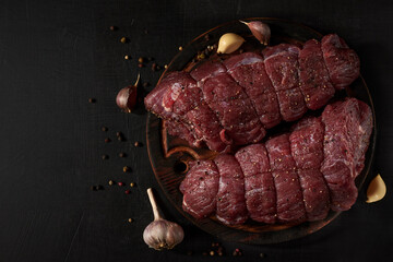 Pair of beef fillet, prepared for cooking with seasoning on a cutting board. Rustic style. Top view photo with copyspace.