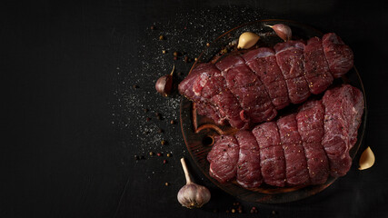 Pair of beef fillet, prepared for cooking with seasoning on a cutting board. Rustic style.