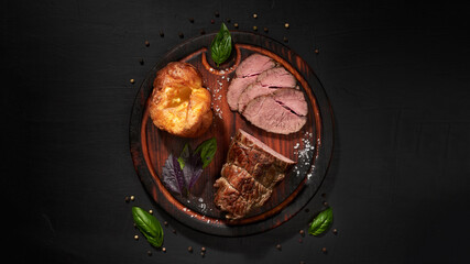 Roastbeef, yorkshire puddnings, basil leaves on a wooden cutting bords .