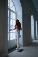 Full size body length of lovely charming beautiful nice stylish girl doing everyday warming up exercises in modern light white interior next to big window