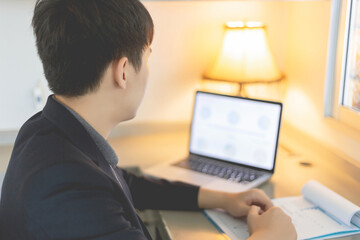 Business partners concept a young businessman using a laptop revising annual sales summary