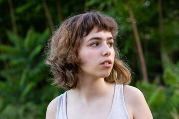 Naklejka premium Serious teenager girl looking angry. Curly pretty young girl outside