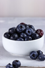Freshly picked blueberries in a bowl. Juicy and fresh blueberries with green leaves on rustic table. Concept for healthy eating and nutrition