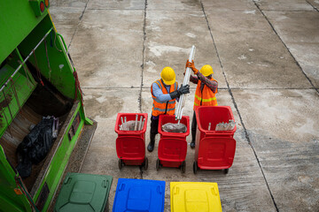 Rubbish cleaner man working with green garbage truck loading waste and trash bin at city,Waste collectors at work,Top view.