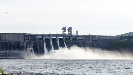 Discharge of excess water from floodgates during flooding. Hydroelectric power plant close-up.