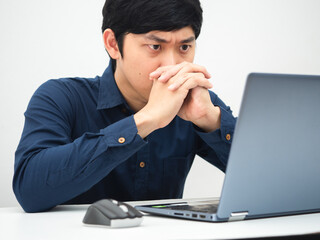 Man working from home and looking at laptop on the table feeling serious about job