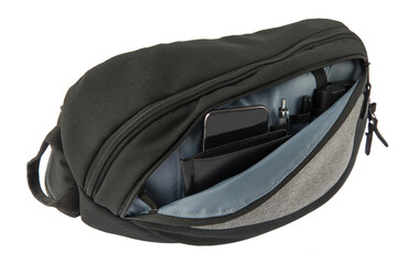 Isolated close up studio shot of front zipper compartment pocket of pro photographer black camera bag holding wallet smartphone pen marker battery and sutstitute inside in front of white background