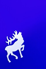 Christmas greeting card with handmade white deer on blue background. Winter Holiday concept.