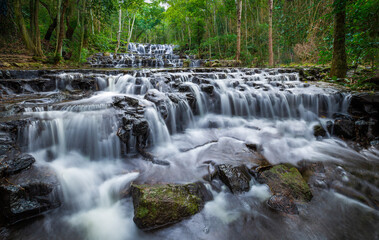 Smooth flowing waterfall on the stage of rock in the deep jungle.