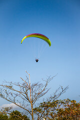 A yellow paraglider is flying over the mountain