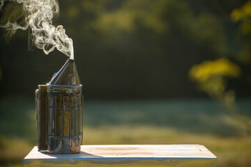 Bee smoker with smoke on the beehive in the nature with copy space