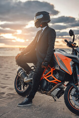 Businessman biker resting on beach with his custom motorcycle