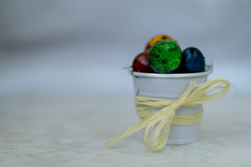quail colored Easter eggs in a bucket with a bow