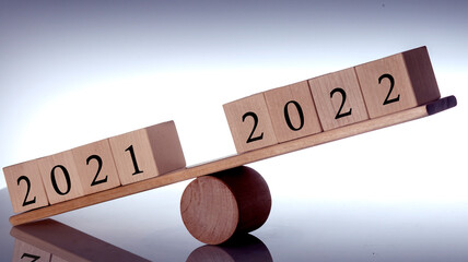 Wooden block balance between 2021 and 2022 on the light background