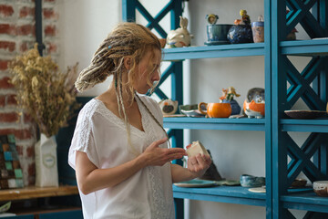hostess of the ceramic workshop lays out her ceramic dishes on the shelves. feng shui concept. Small business office
