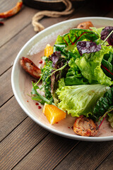 Salad with roasted duck greens and oranges mix on a wooden background