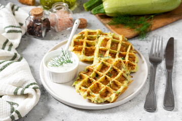 Homemade zucchini waffles in a white plate on a light gray culinary background closeup