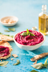red beetroot hummus on blue background, lemon, sesame, olive oil, pita. Middle eastern, jewish, arabic cuisine.