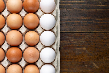 Chicken eggs in a tray on a wooden table.