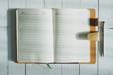 A pen and note book open on wood table in online learning at home concept.