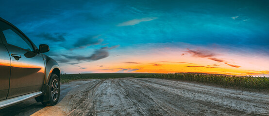 Green SUV Car Parked On Field Country Road Through Summer Maize Field In Amazing Sunset Time. Summertime. © Great Brut Here