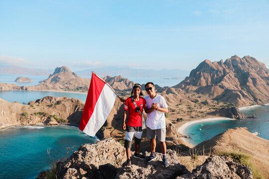 Two Indonesian man on top mountain and holding Indonesian flag