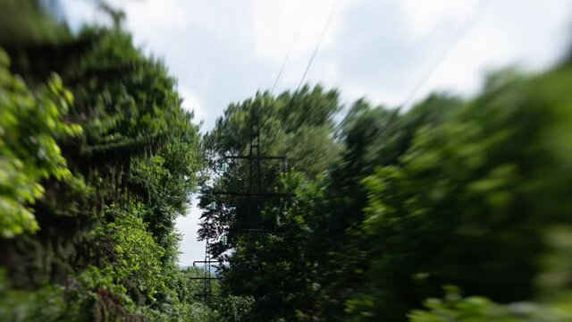A timelapse of clouds near a power line, among trees in the forest. Taken on the "lens baby" with the effect titl shift