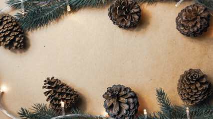 Christmas decorations, light, pine cone and branches on a craft papaer background for the concept of holidays and festival celebrations