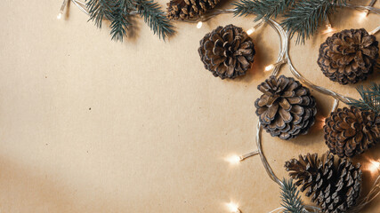 Christmas decorations, light, pine cone and branches on a craft papaer background for the concept of holidays and festival celebrations - 450814798
